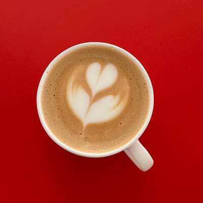 A top down view of a cup of coffee, the foam shaped into a heart design.